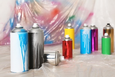 Photo of Used cans of spray paint indoors. Space for text