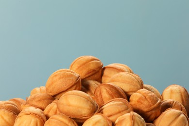 Photo of Freshly baked walnut shaped cookies against light blue background, closeup. Homemade pastry filled with caramelized condensed milk