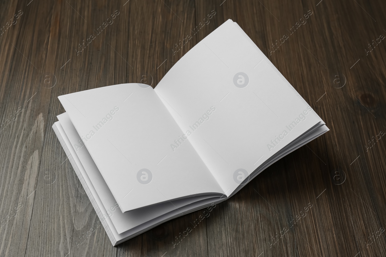 Photo of Open blank paper brochure on wooden table. Mockup for design