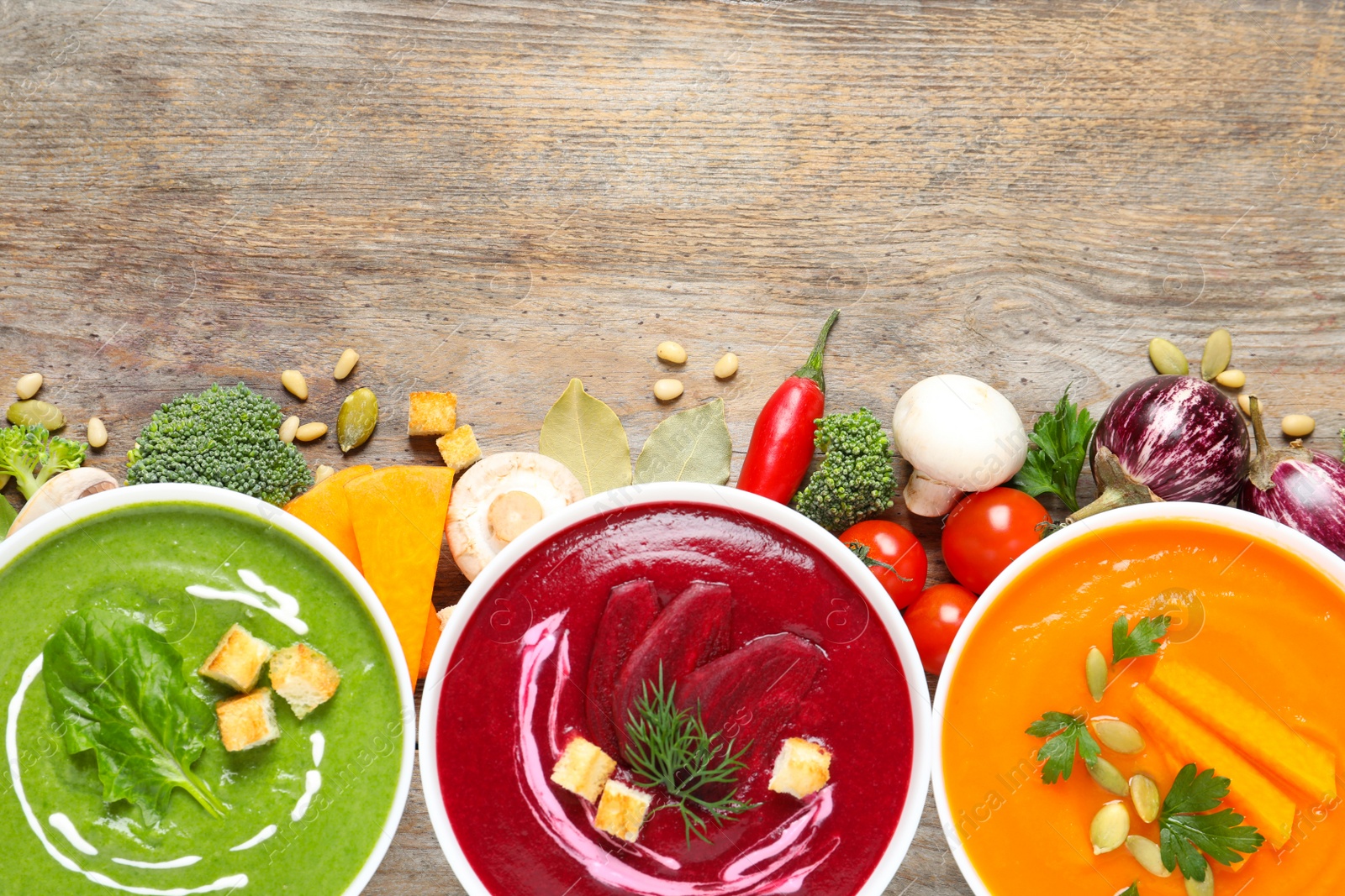 Photo of Various cream soups, ingredients and space for text on wooden background, flat lay. Healthy food