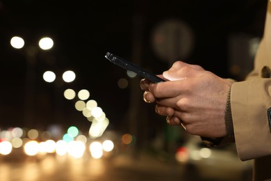 Photo of Man using smartphone on night city street, closeup. Space for text