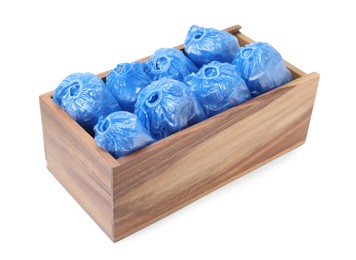 Photo of Rolled blue shoe covers in wooden crate isolated on white