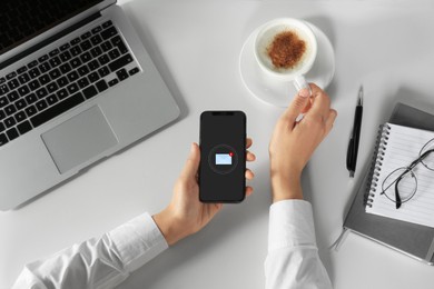 New message notification. Woman with mobile phone taking cup of coffee at table, top view