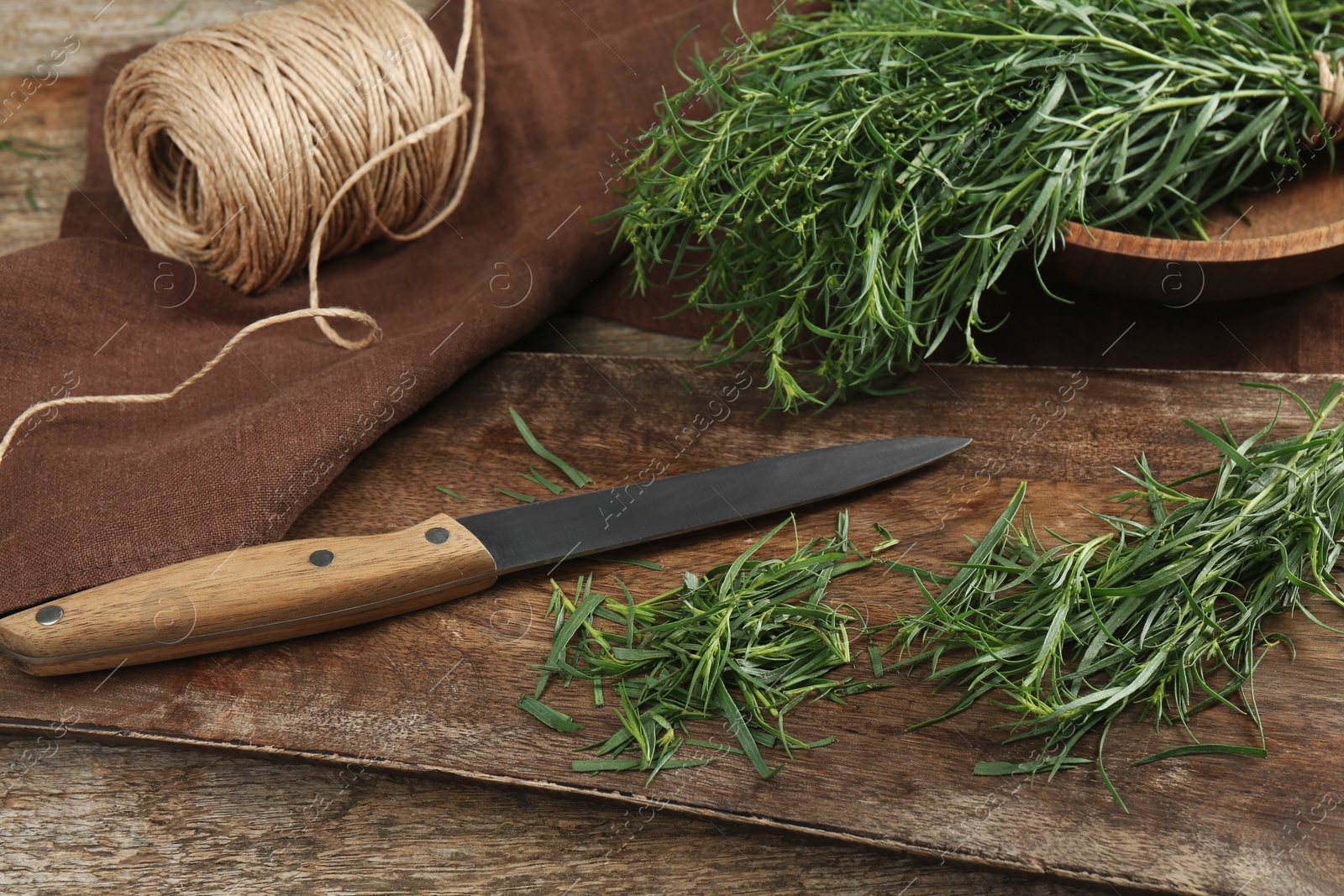 Photo of Fresh whole and cut tarragon sprigs on wooden table