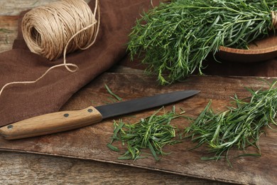 Photo of Fresh whole and cut tarragon sprigs on wooden table