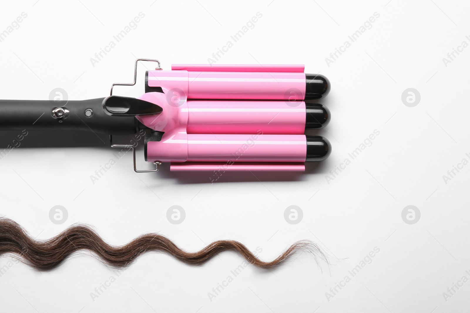 Photo of Modern triple curling iron and brown hair lock on white background, top view