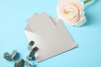 Beautiful ranunculus flower and envelope with card on color background. Space for text