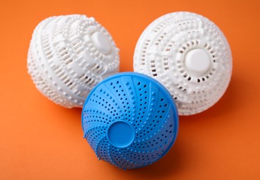 Photo of Dryer balls for washing machine on orange background. Laundry detergent substitute