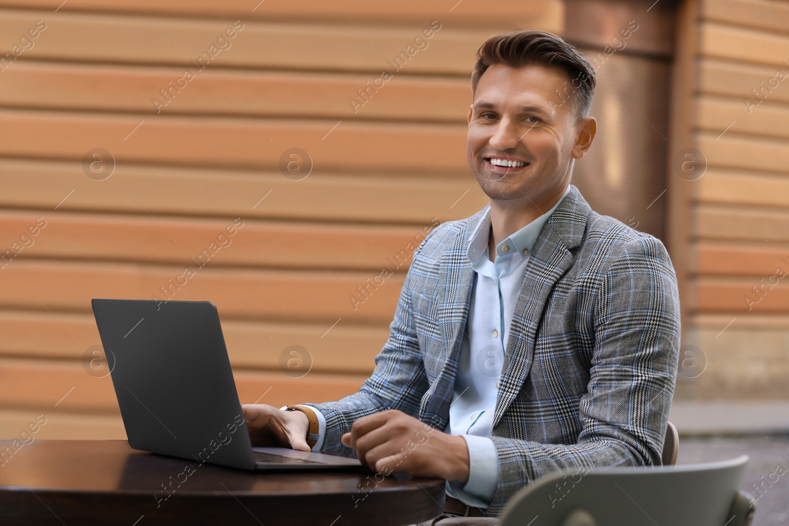 Photo of Handsome man working on laptop at table in outdoor cafe