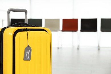 Photo of Yellow suitcase with label indoors, space for text. Travel insurance