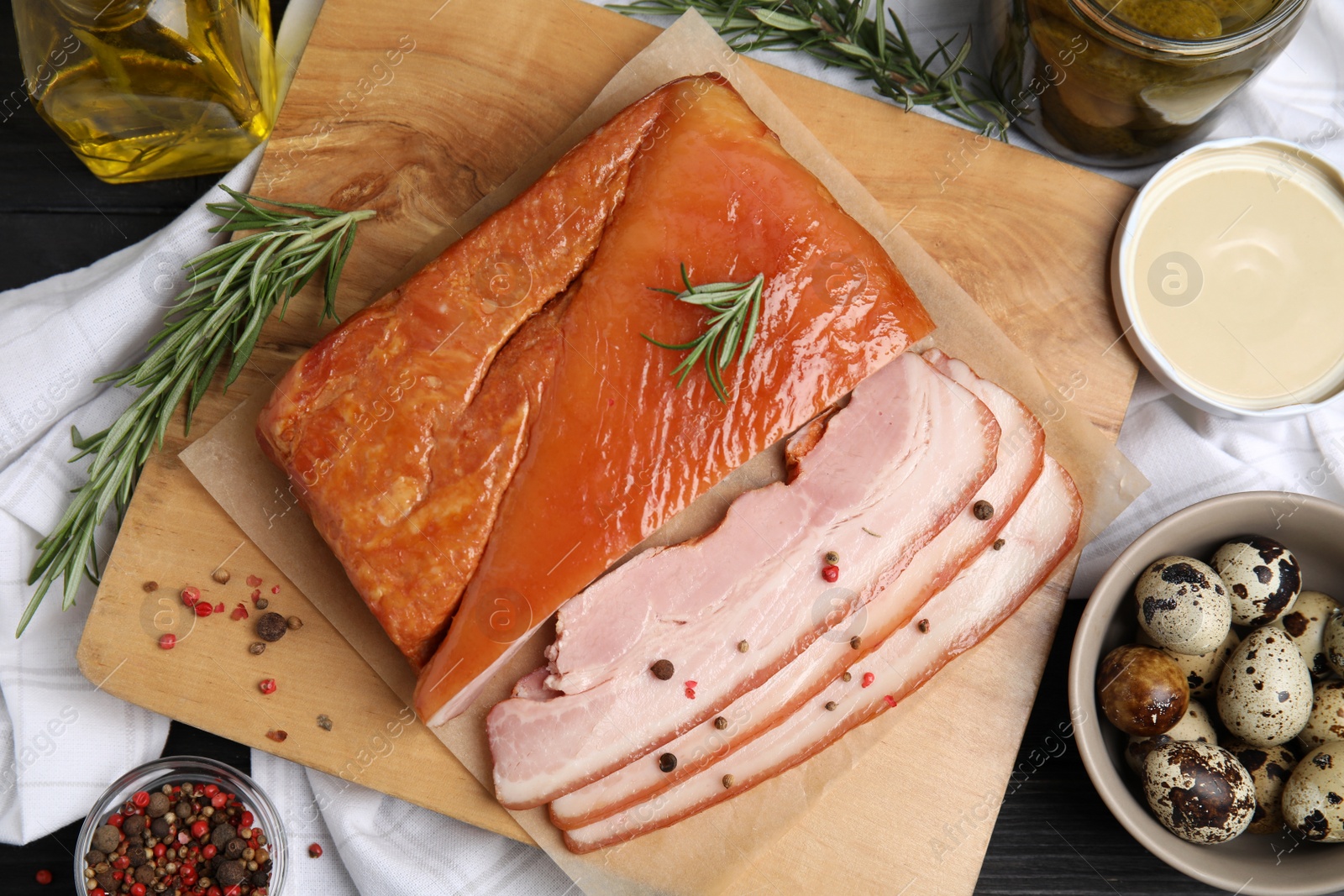 Photo of Flat lay composition with delicious smoked bacon on black wooden table