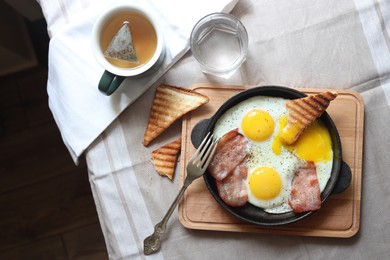 Tasty fried eggs with bacon and toasts served on table, top view