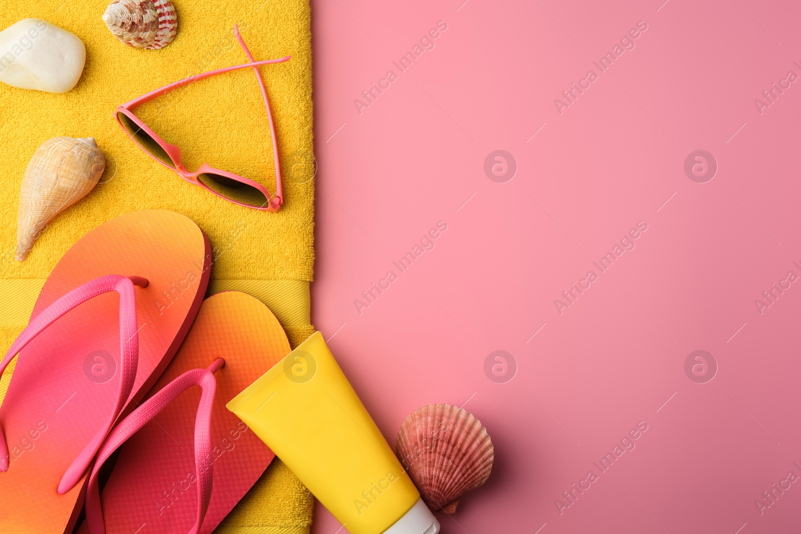 Photo of Flat lay composition with sunscreen and beach accessories on pink background, space for text