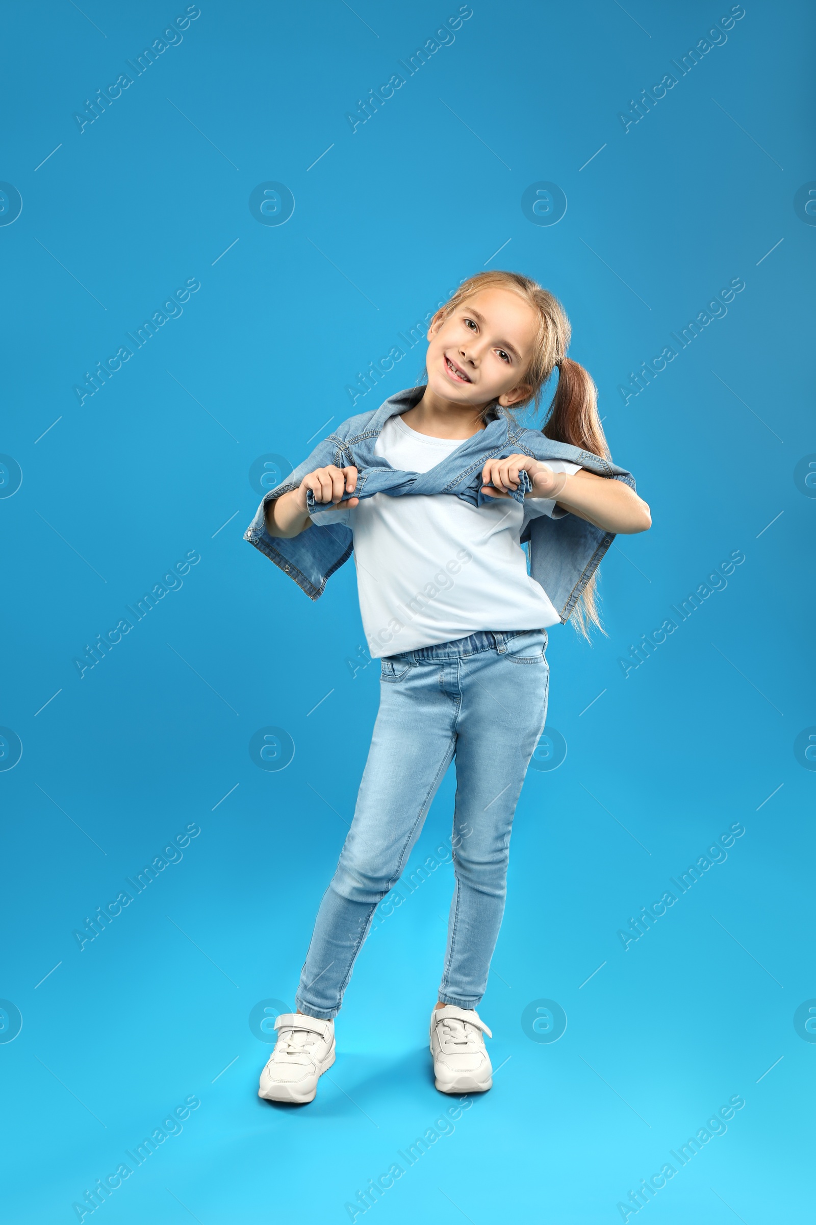 Photo of Cute little girl posing on blue background