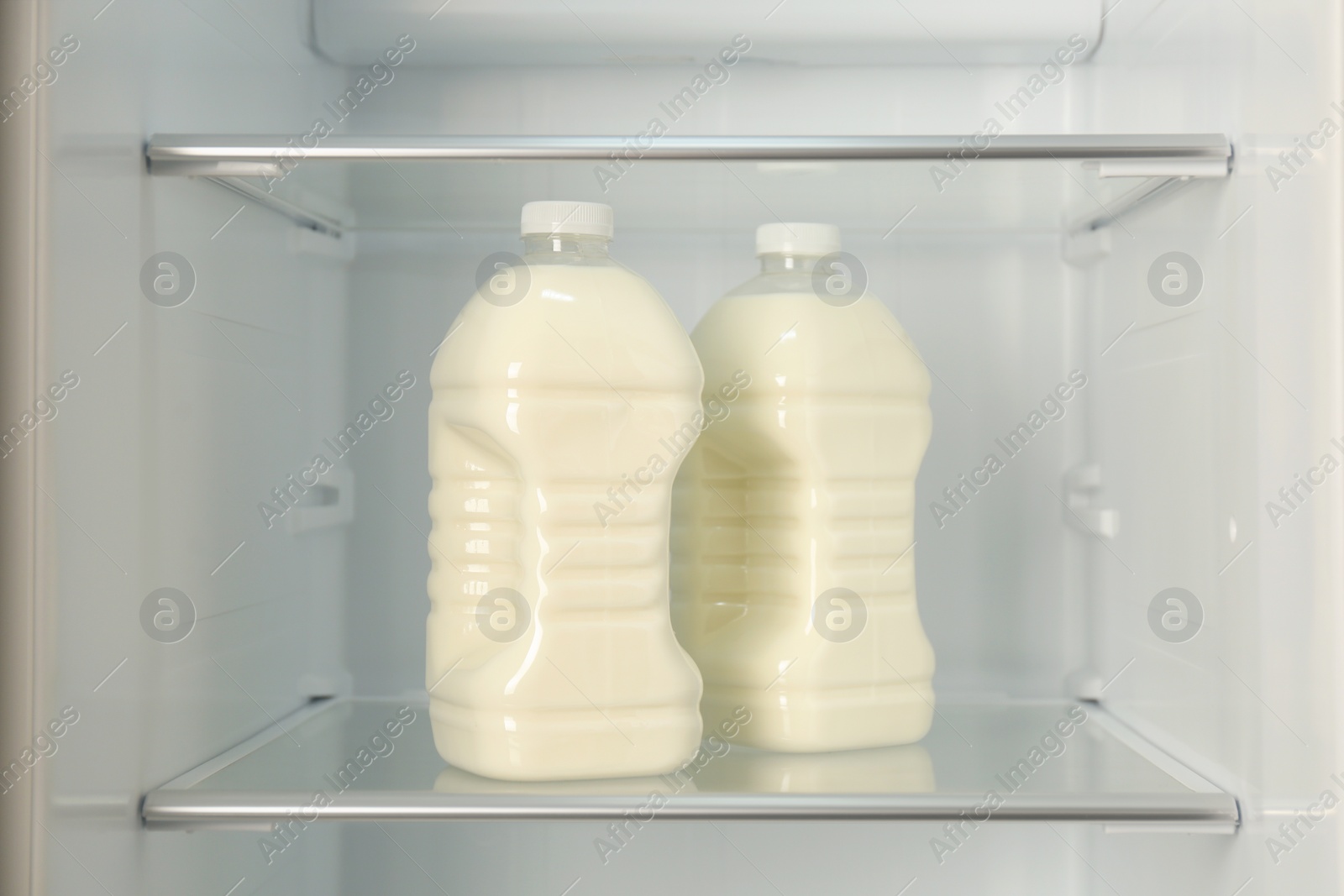 Photo of Gallons of fresh milk in refrigerator, closeup