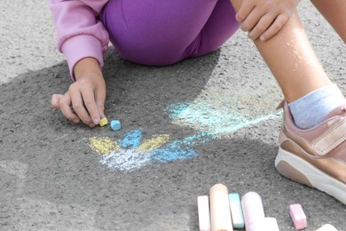 Photo of Little child drawing flower with chalk on asphalt, closeup