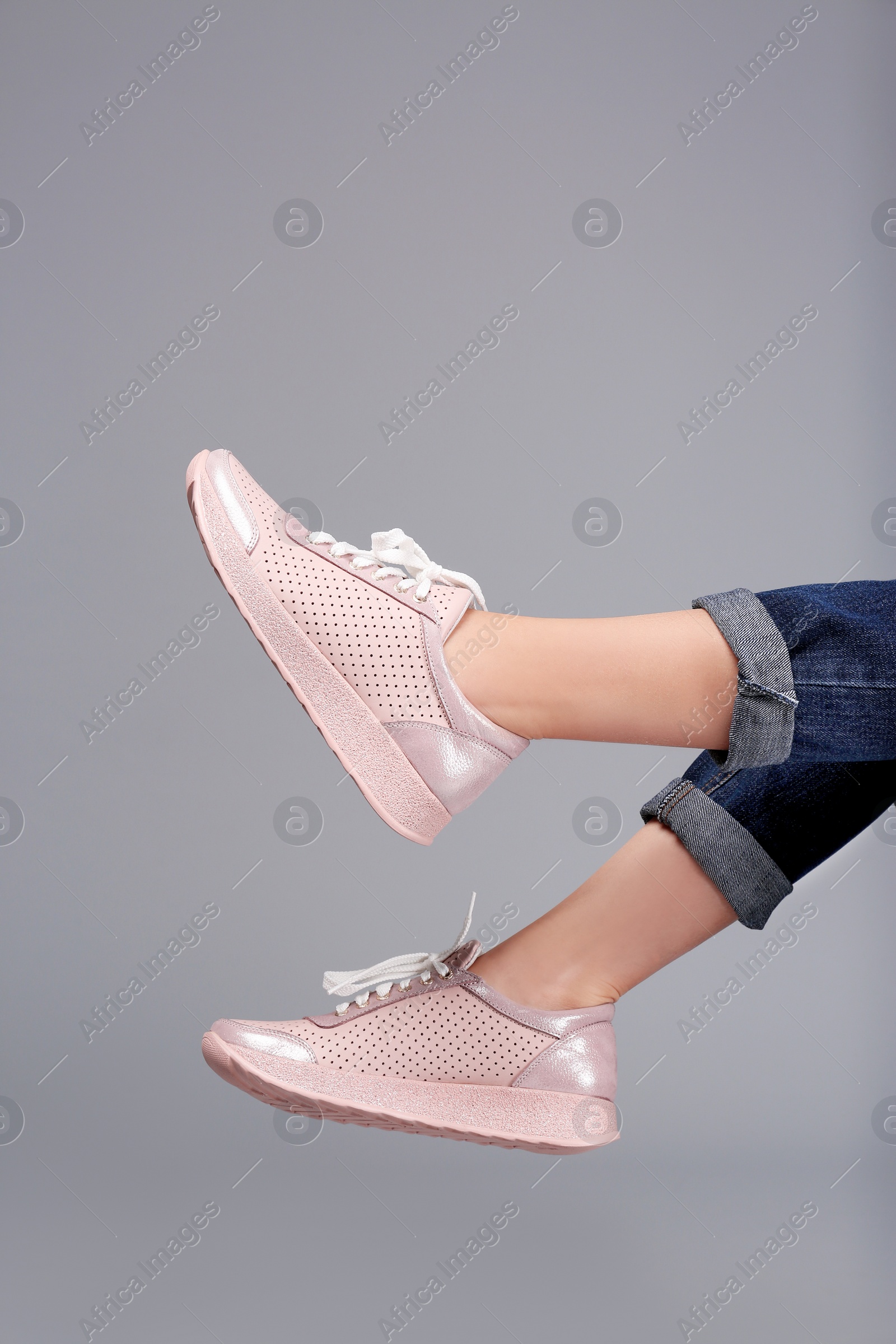 Photo of Woman in stylish sport shoes on grey background