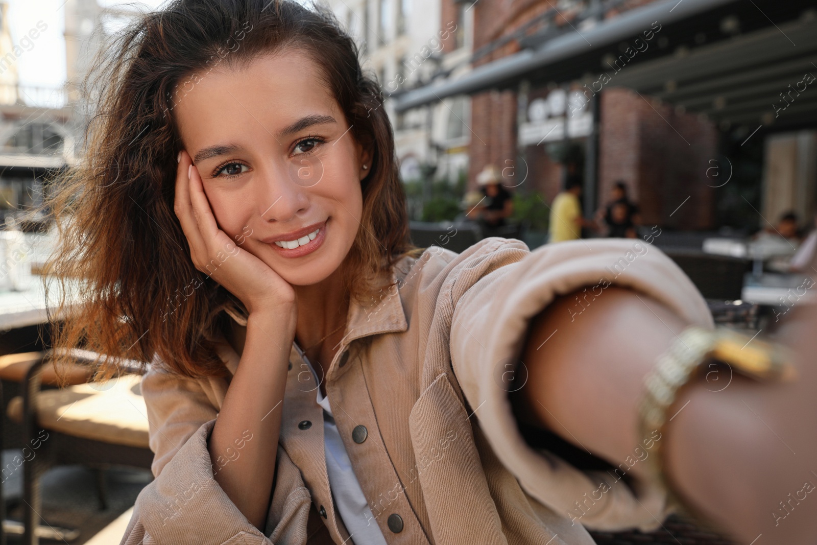 Photo of Happy young woman taking selfie in outdoor cafe