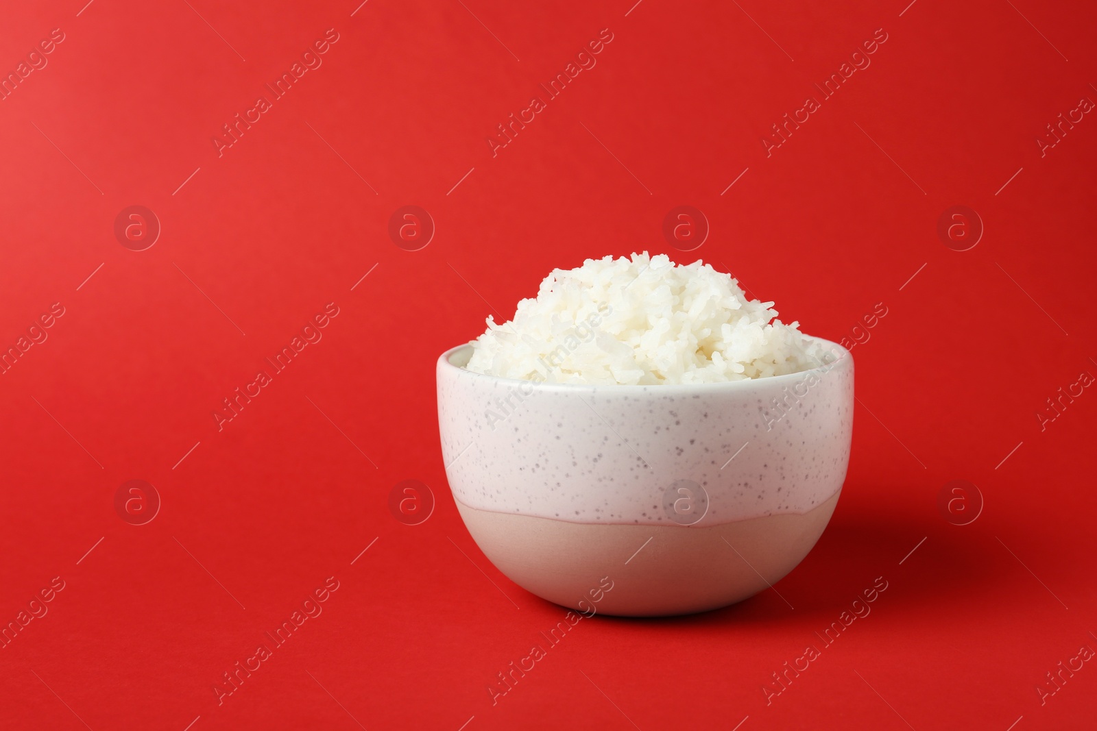 Photo of Bowl of boiled rice on color background. Space for text