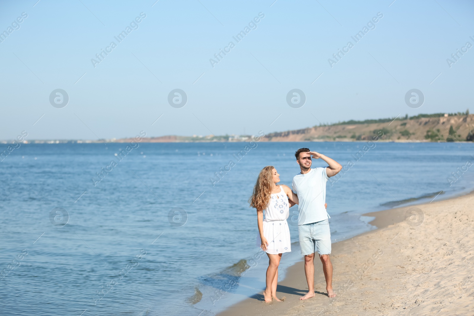 Photo of Happy young couple holding hands at beach on sunny day