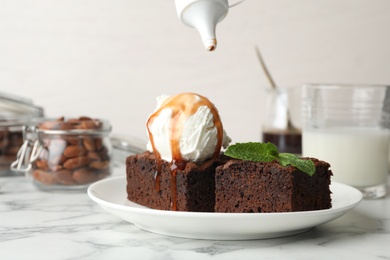 Photo of Plate with fresh brownies and ice-cream on table. Delicious chocolate pie