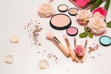 Photo of Composition with makeup brushes, cosmetic products and flowers on white background