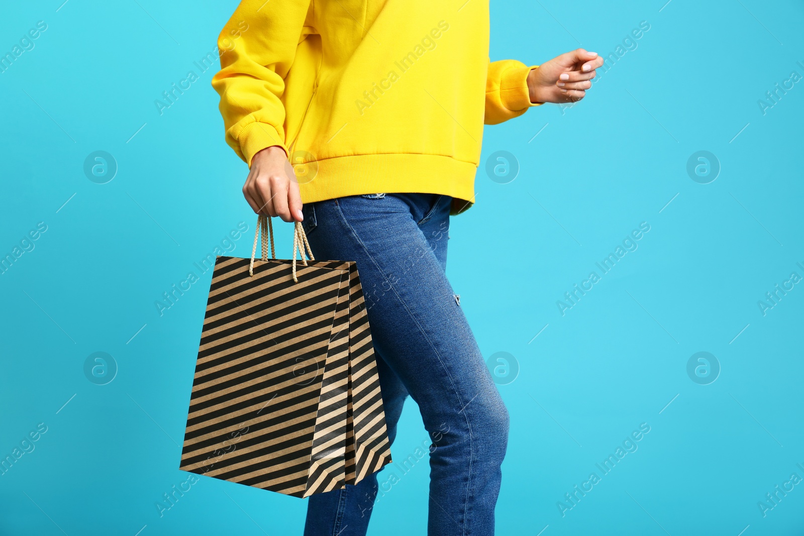 Photo of Young woman with paper bags on blue background, closeup