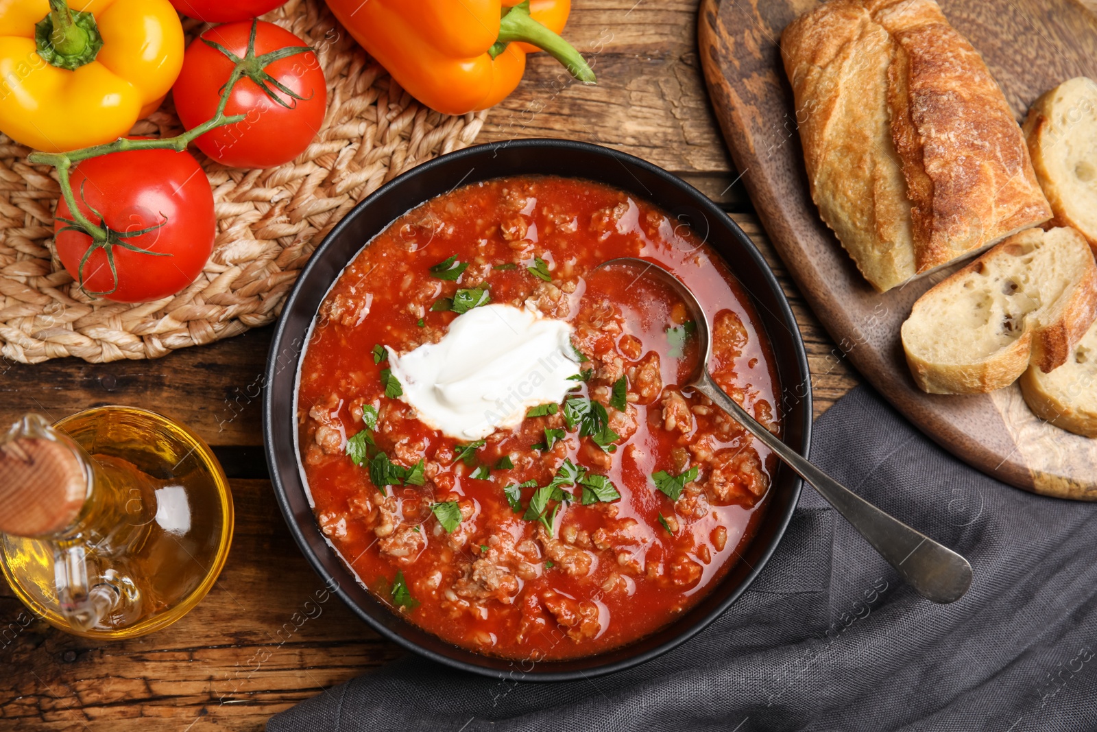 Photo of Bowl of delicious stuffed pepper soup served on wooden table, flat lay