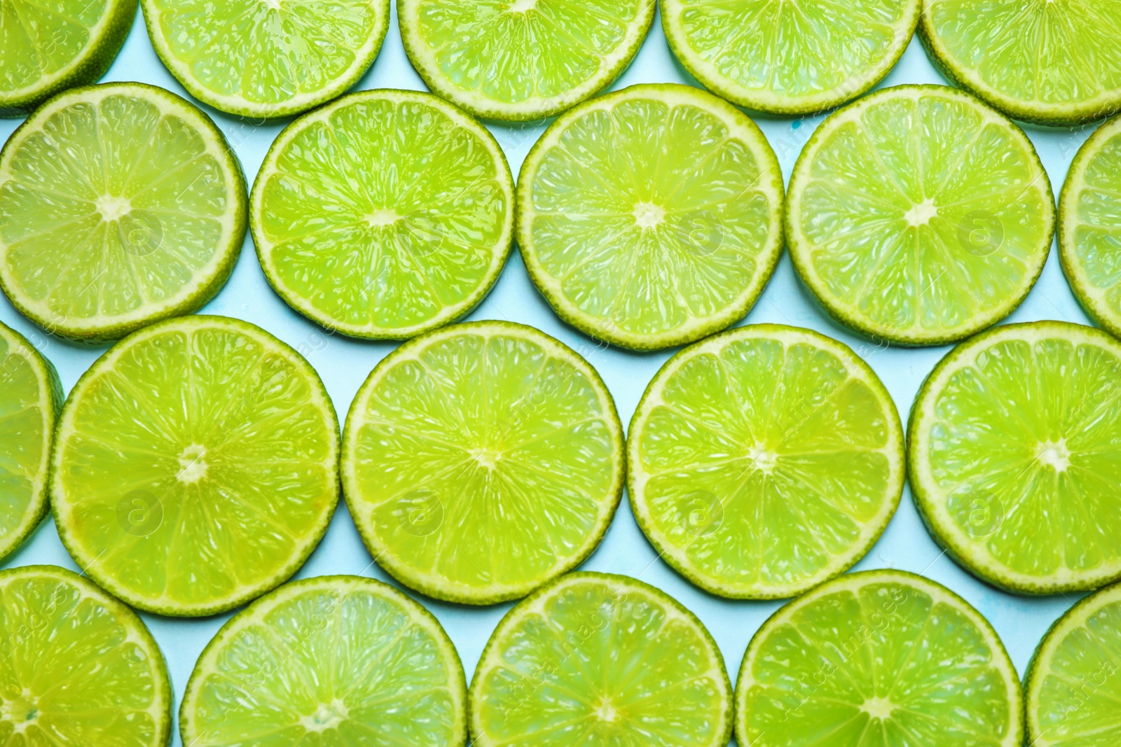 Photo of Juicy fresh lime slices on light blue background, flat lay