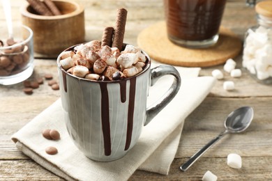 Photo of Delicious hot chocolate with marshmallows and cocoa powder in cup on wooden table