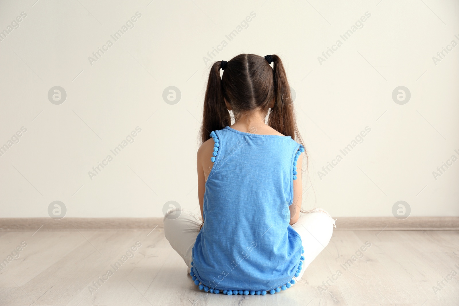 Photo of Lonely little girl sitting on floor in room. Autism concept