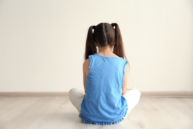 Lonely little girl sitting on floor in room. Autism concept