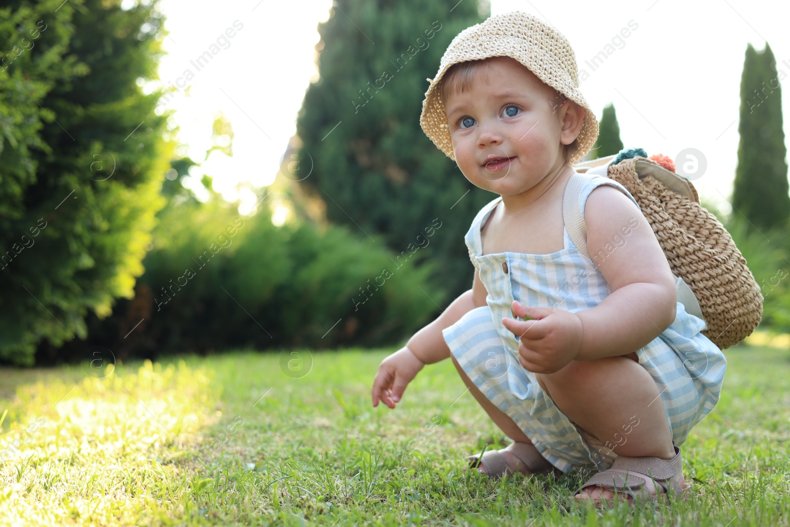 Photo of Cute little girl in stylish clothes with knitted backpack outdoors on sunny day. Space for text