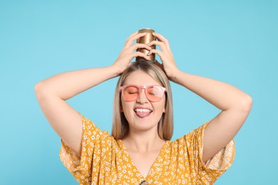 Beautiful happy woman holding beverage can against light blue background