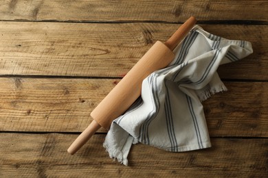 Photo of Rolling pin and kitchen towel on wooden table, top view. Space for text