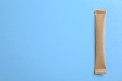 Photo of Beige stick of sugar on light blue background, top view. Space for text