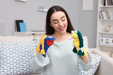 Happy woman performing puppet show on sofa at home