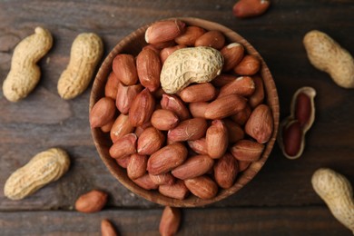 Photo of Fresh peanuts in bowl on wooden table, flat lay