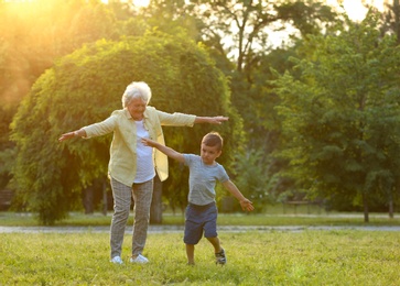 Photo of Little boy and his grandmother having fun in park
