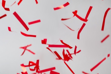 Photo of Shiny red confetti falling down on light grey background