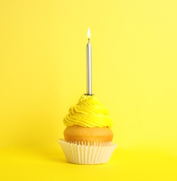 Photo of Birthday cupcake with candle on yellow background