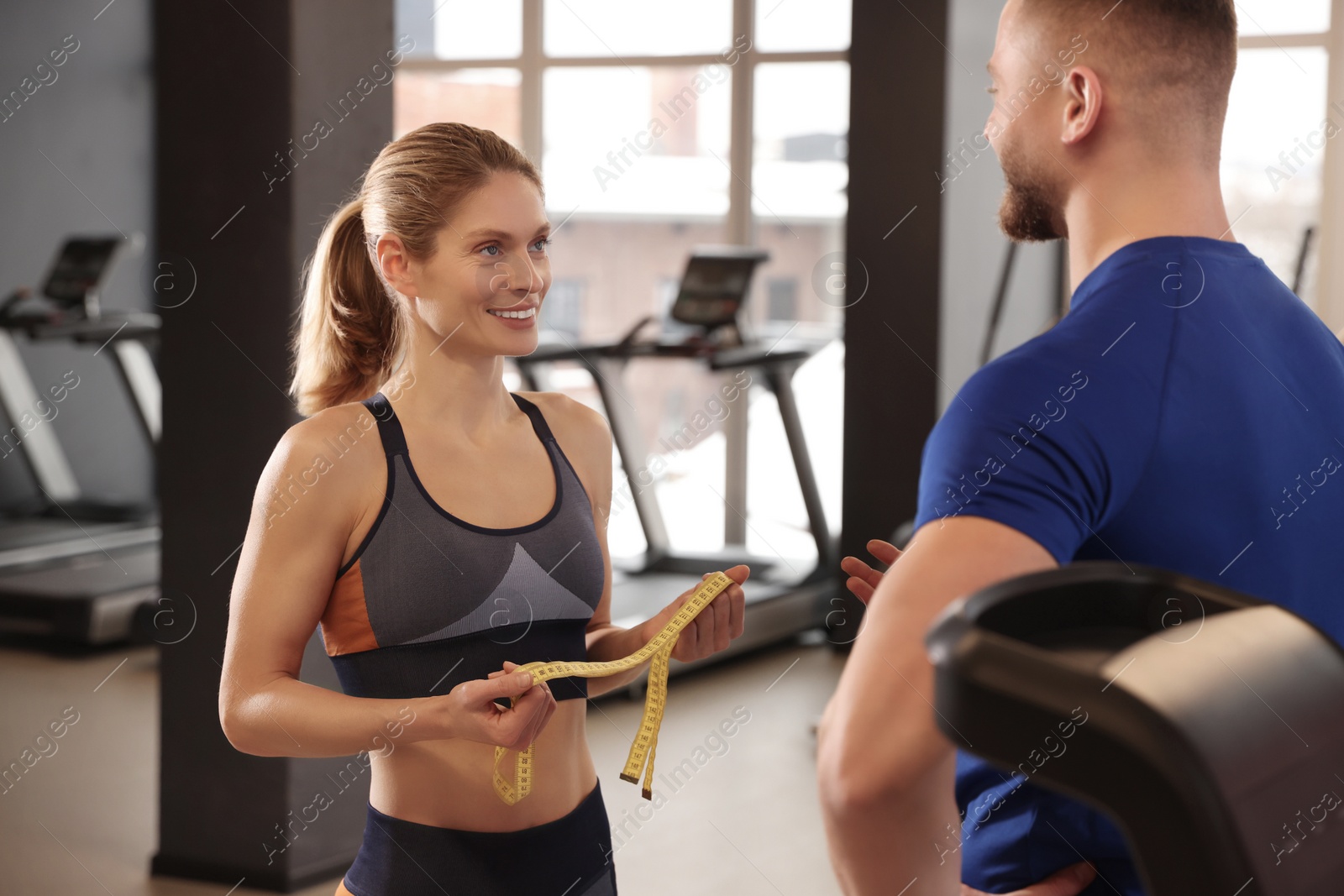 Photo of Trainer having discussion with woman in gym