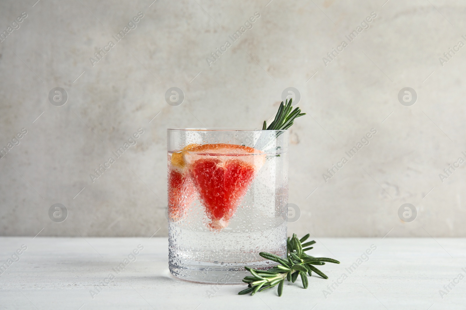 Photo of Glass of infused water with grapefruit slices on table