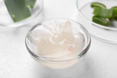 Photo of Aloe vera gel and slices of plant on white background, closeup