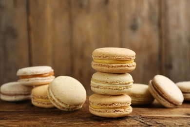 Photo of Delicious macarons on wooden table. Sweet dessert
