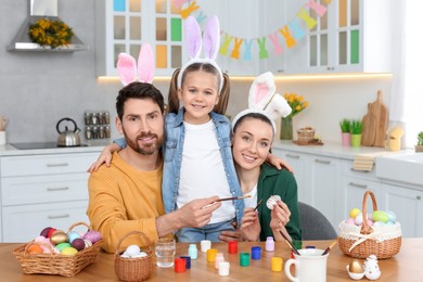 Photo of Happy family with Easter eggs at table in kitchen