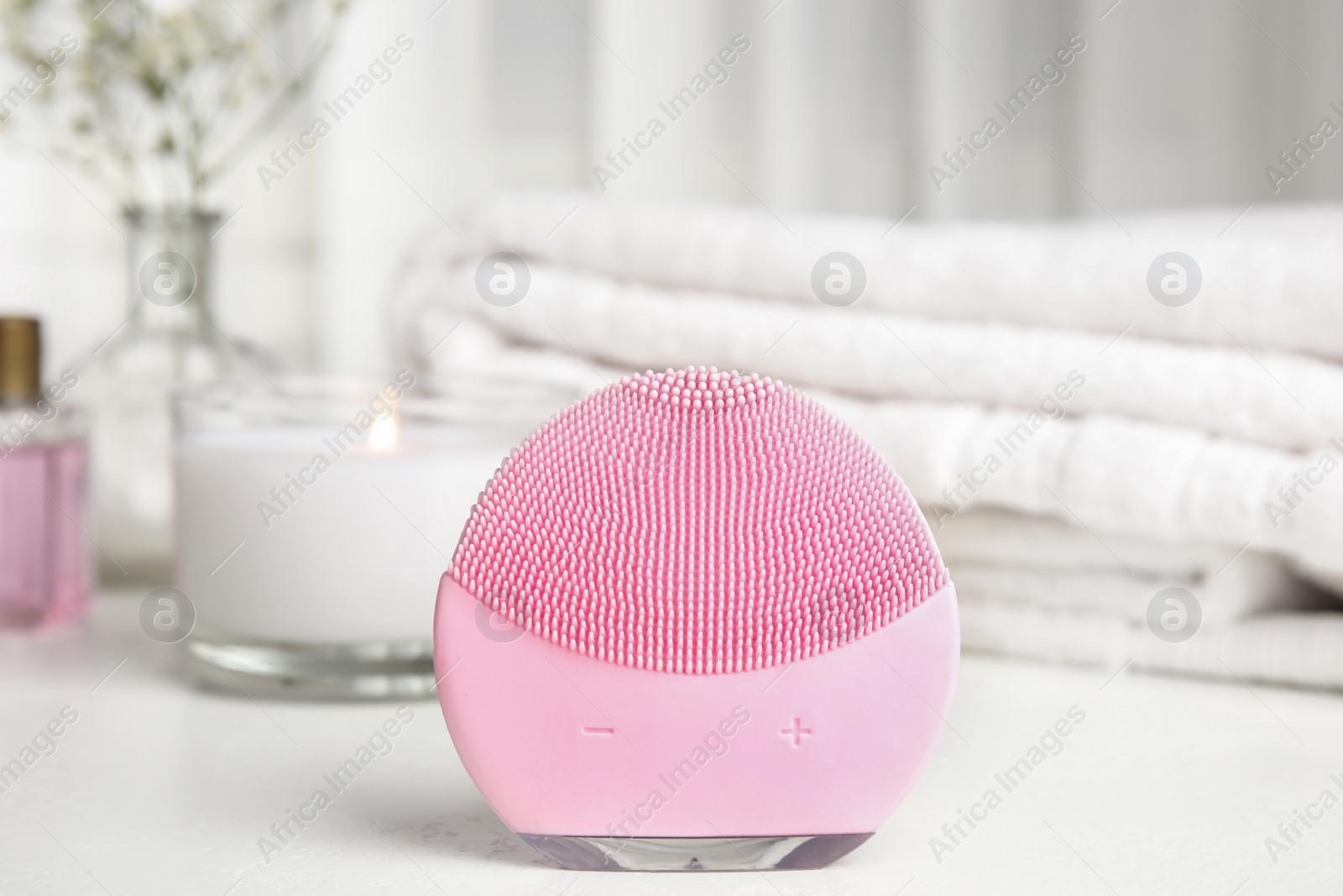 Photo of Modern face cleansing brush on white table. Cosmetic accessory