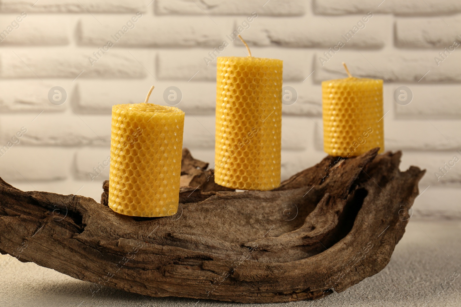 Photo of Beautiful yellow beeswax candles on snag indoors
