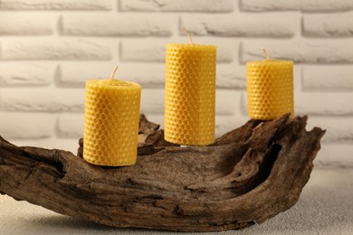 Beautiful yellow beeswax candles on snag indoors