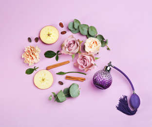 Photo of Beautiful flat lay composition with bottle of perfume, apple, cinnamon and flowers on lilac background